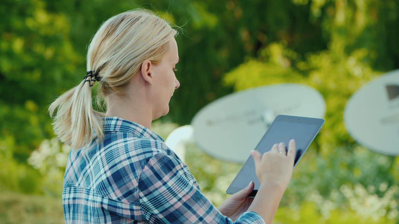 mujer sintoniza antenas parabólicas al aire libre utiliza tablet