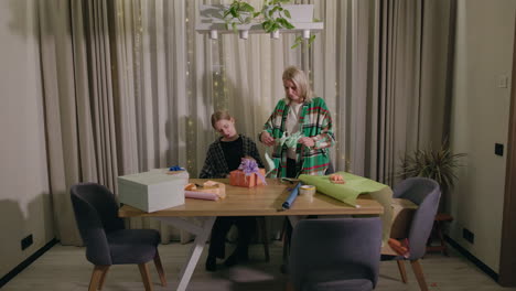 mother and daughter wrapping gifts together at home