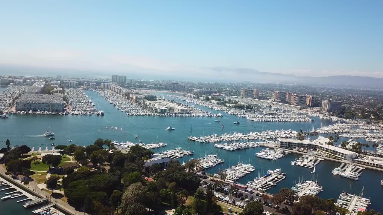 Aerial wide shot of marina del Rey with boats and hotel building. Sunny day in summer. Cruising boats on blue water. California, USA
