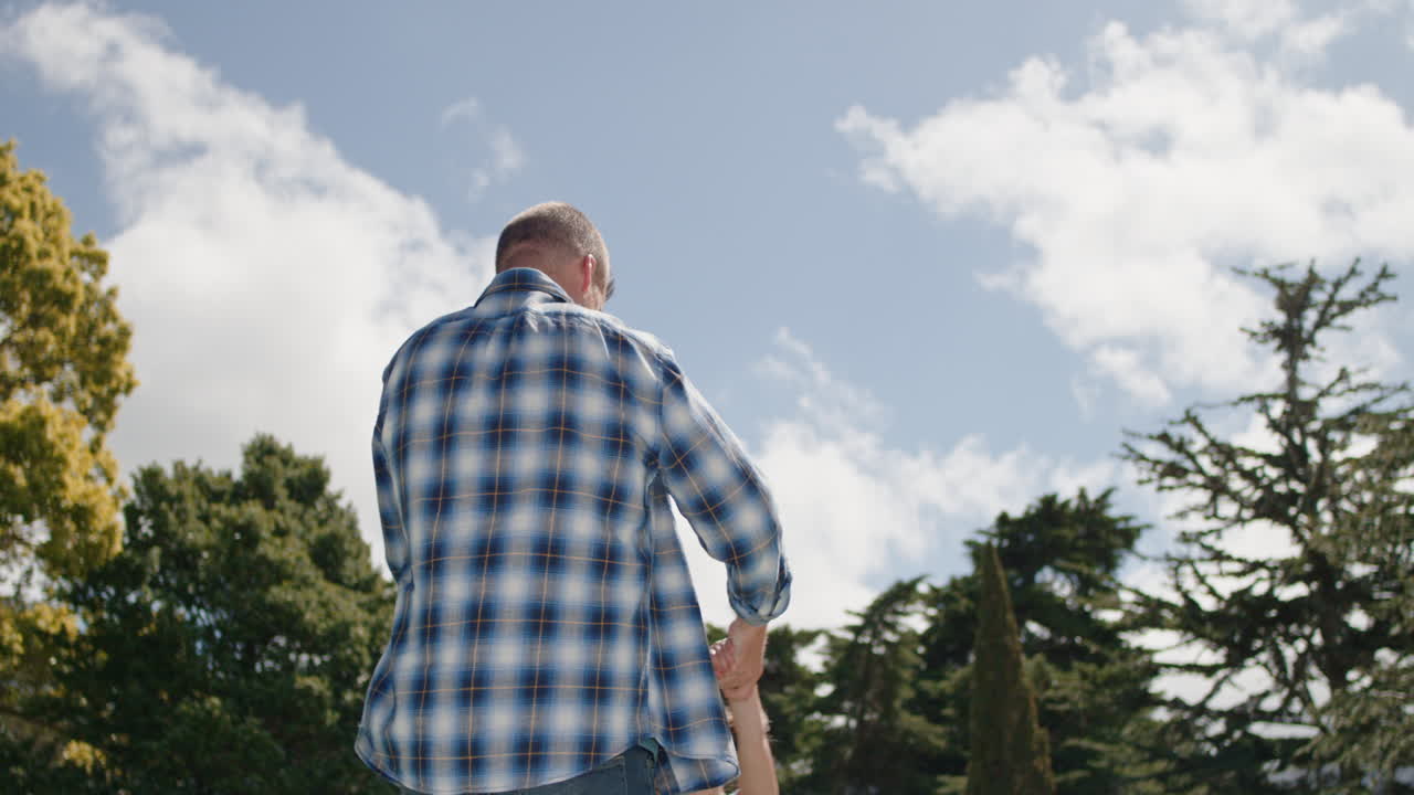 행복한 아버지와 딸은 뒷마당 정원에서 함께 놀고 있습니다. 행복한 어린 소녀는 아빠와 함께 재미를 느끼고 있습니다. 아이를 잡고 놀면서 아이를 흔들고 있습니다. 야외에서 어린 시절의 자유를 즐기고 있습니다.