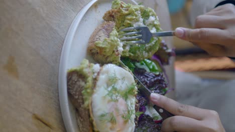 person eating avocado toast with a fried egg for breakfast