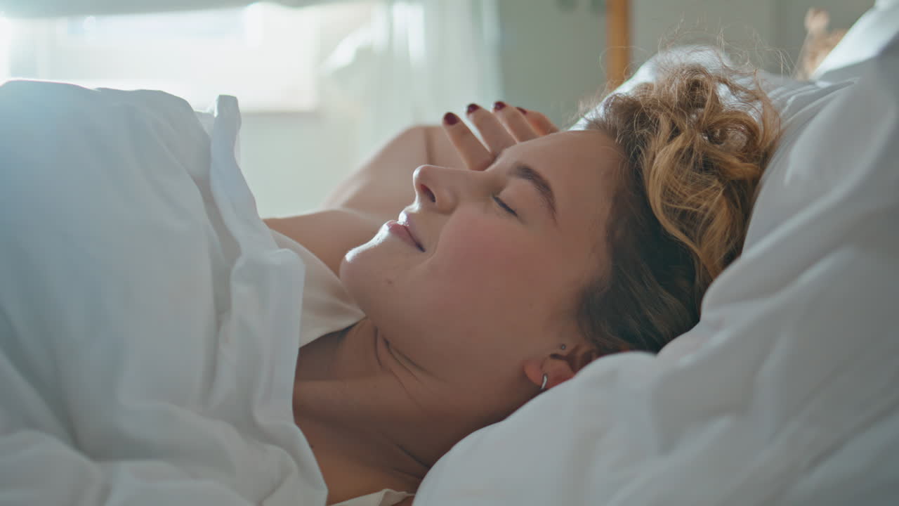 Peaceful girl waking bed in early morning. Closeup smiling blonde stretching