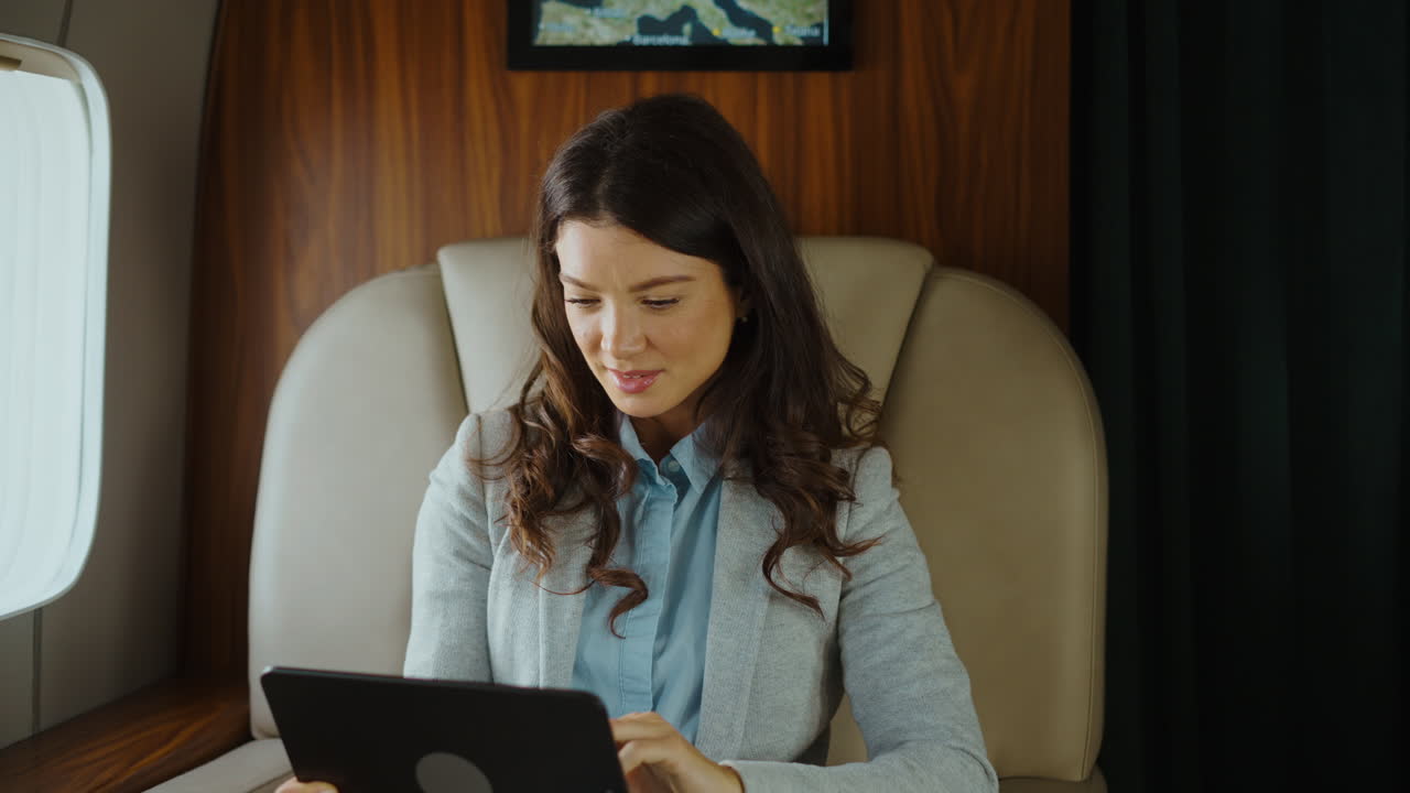 Woman using tablet in a private jet with a flight attendant