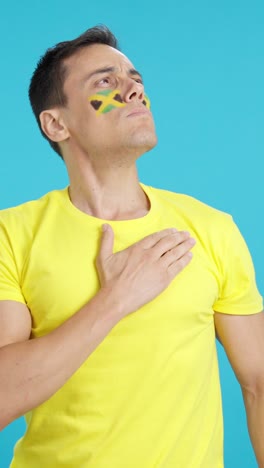 man listening to the jamaica national anthem with solemnity