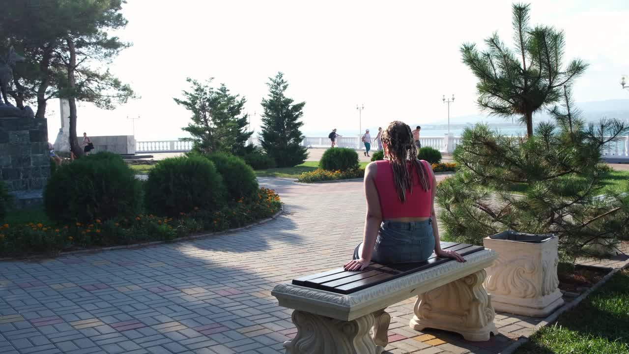Woman Sitting on a Bench in a Park by the Sea