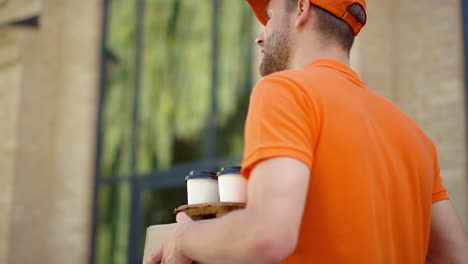 delivery man going with box and cup holder. courier working for delivery service