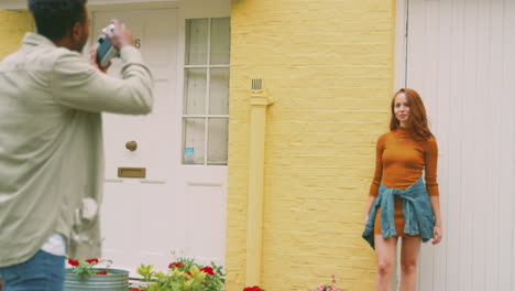 woman posing and man taking photos on camera as young couple travel through city together