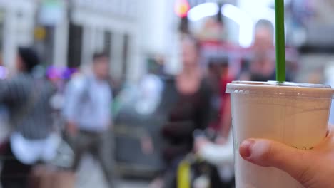 hand holding coffee cup amidst busy london street