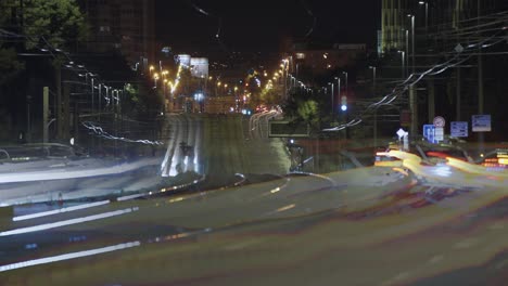 a long-exposure shot of a city street at night, filled with bright, colorful light trails and glowing streetlights.