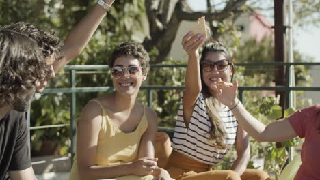 smiling friends raising hands with slices of pizza up