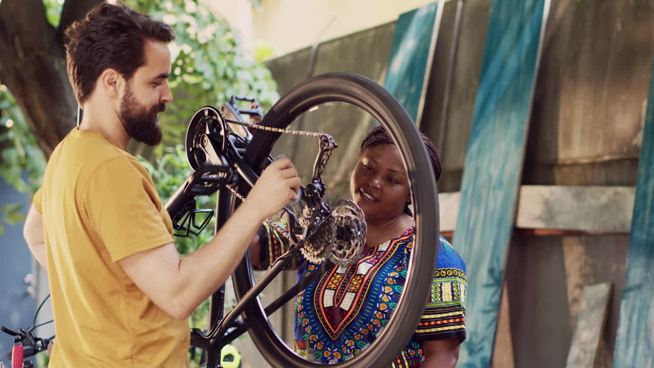 pareja interracial engrasando las ruedas de la bicicleta