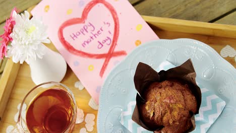 cupcake, tea, flower vase and happy mothers day greetings card in tray