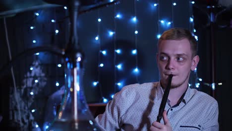 man smoking hookah in a nightclub