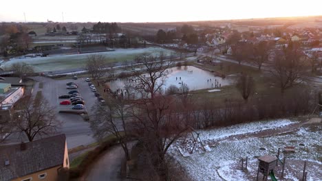 vista aérea de un lago congelado con patinadores de hielo en el hielo - toma de drone