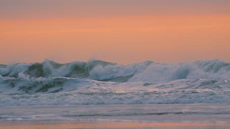 sunrise ocean slow motion footage of powerful waves arriving on beach with orange sunlight in background. beautiful nature footage prores 4k.