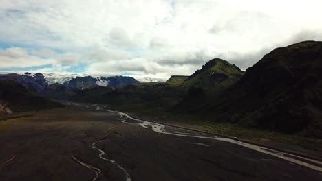 Aerial-landscape-view-of-a-river-flowing-through-a-valley,-in-the-Fimmvörðuháls-area,-Iceland