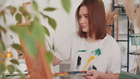 a red haired young female artist painting a frame