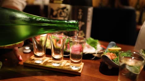 sequence of sake being poured into multiple glasses