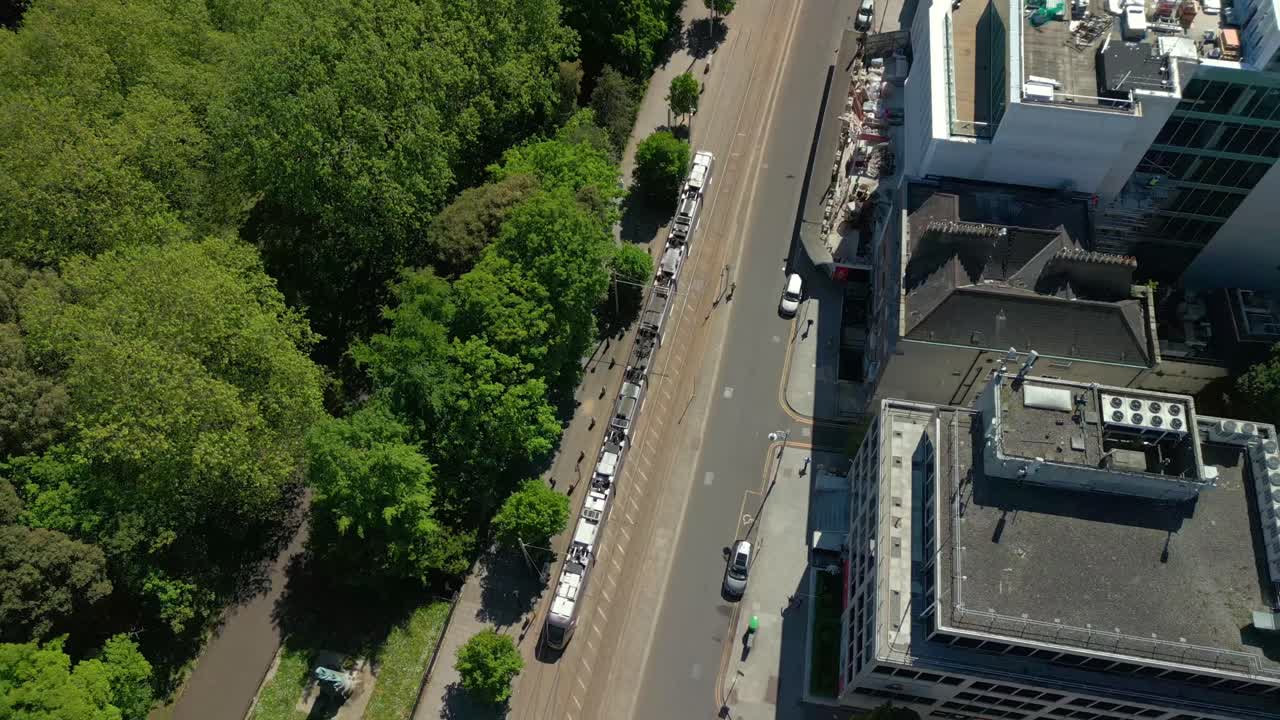 Wide, reversing aerial video of the Luas Tram System operating in Dublin City Centre, County Leinster, Ireland, on a bright and sunny day. Filmed in 4K, 60FPS and with Rec709 color.