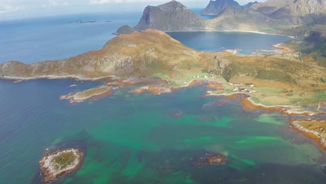 Aerial-view-of-a-couple-at-the-peak-of-a-hike-admiring-the-view-of-the-fjords-and-the-mountains,-Lofoten-Islands,-Norway