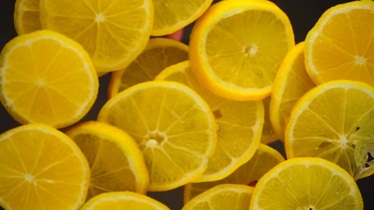 Fette di limoni cadono su una superficie trasparente. Vista dal basso.