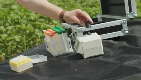 trabajador de laboratorio que sostiene artículos de vidrio profesionales y prueba brotes de plantas antes de la cosecha en el campo.