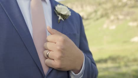 joven o novio parado afuera con un traje formal sosteniendo una chaqueta con un anillo de bodas visible 1080p 60fps