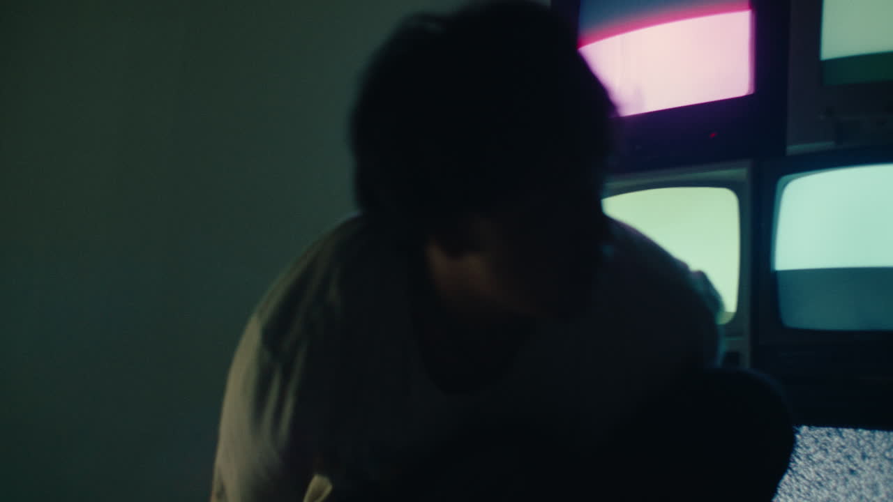 Young alternative boy Sitting Alone in the Dark room with Vintage crt TVs, standing up and leaving after a mental crisis