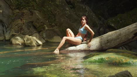 Hispanic-girl-in-bikini-laying-on-a-fallen-log-in-a-plunge-pool-on-a-tropical-island-in-the-Caribbean