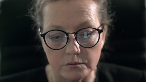 in glasses of a mature woman currency graph are displayed while she is studying stock exchanges