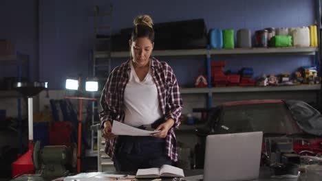 Mecánica-Femenina-Leyendo-Un-Documento-Mientras-Está-De-Pie-En-Una-Estación-De-Servicio-De-Automóviles