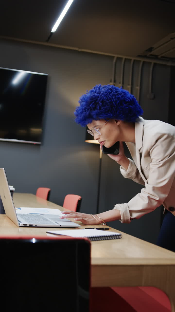 Video verticale di imprenditrice di etnia mista che parla allo smartphone e usa il laptop, slow motion