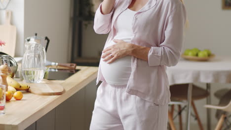 pregnant woman talking on phone in kitchen