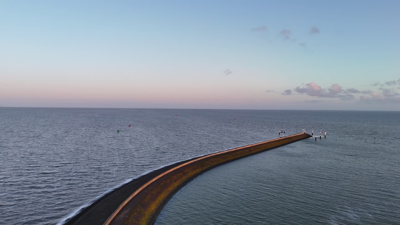 海に伸びる湾曲した港の防波堤のクリアな空撮。