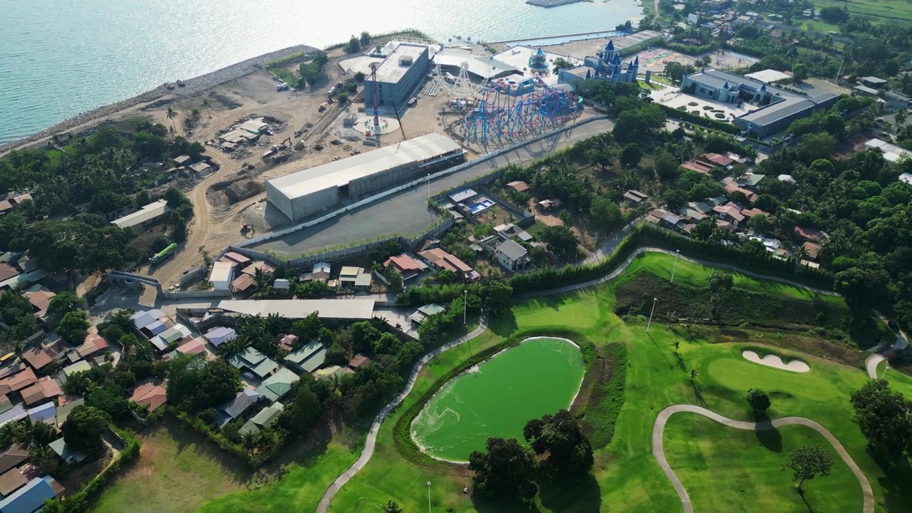 Pullback drone reveal showing detailed resort structures beside Taal Lake and Vineyard Golf Club with cinematic countryside landscape.