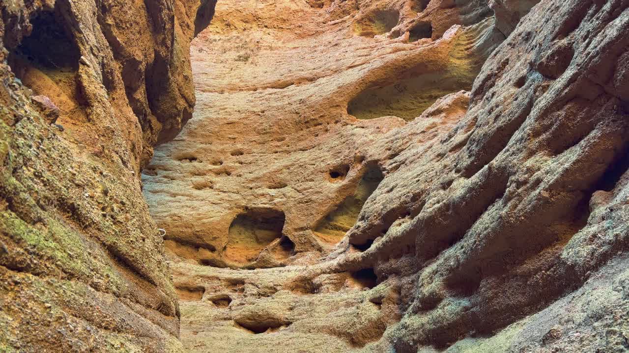 Pingshan Lake Grand Canyon, Zhangye, provincia del Gansu, Cina - Un'imponente camera di arenaria si erge verso l'alto, le sue pareti erose scolpite con incavi lisci e illuminate dalla calda luce del sole - Scatto inclinato