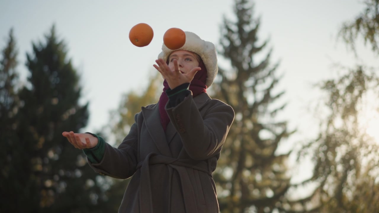 Young Woman Juggling Oranges in a Park During Autumn