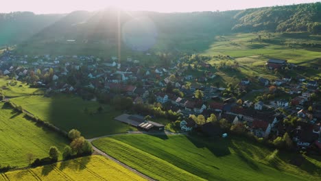 Vista-Aérea-Del-Pequeño-Asentamiento-De-Aldea-Suiza-En-Un-Valle-Cubierto-De-Bosque-Verde-En-El-Cantón-Aargau-Suiza,-Flores-Amarillas-De-Primavera,-Iglesia-De-La-Aldea