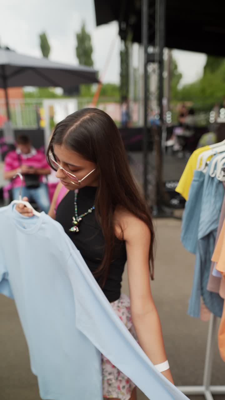 Donna che fa shopping di vestiti a un mercato estivo