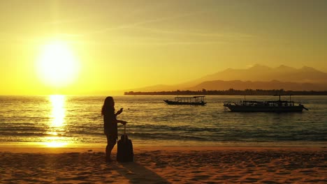 woman with bag stay enchanted with sunset over calm sea, silhouette