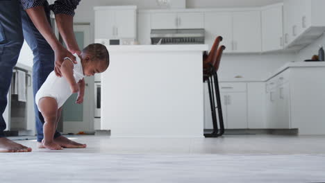 close up of father encouraging smiling baby son to take first steps and walk at home