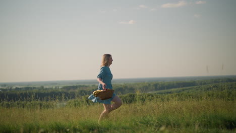 a woman in a flowing blue dress runs through a lush, grassy field toward two young boys dressed in white tops. she carries a basket filled with fruit, capturing a joyful and playful outdoor moment