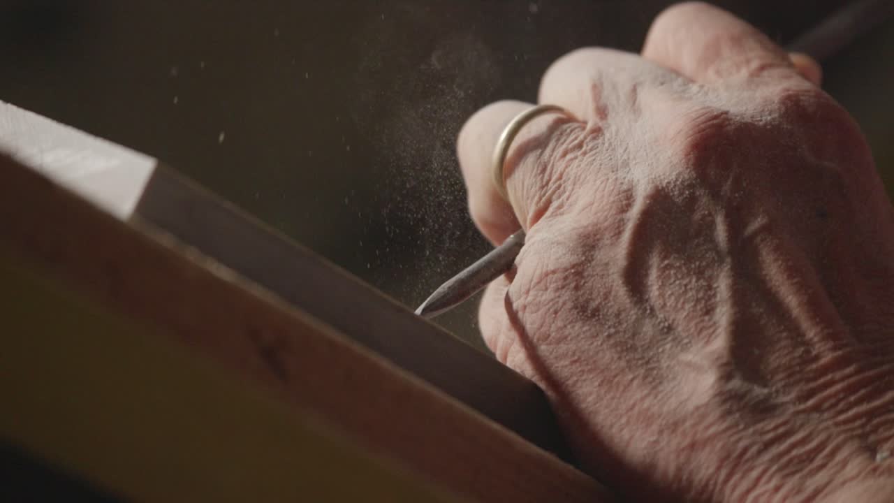 vista de cerca sobre el proceso de tallado fino con herramienta de mano en una piedra.