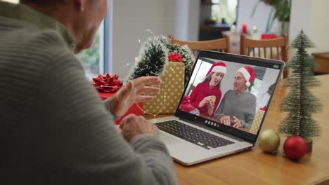 Happy-caucasian-senior-man-on-video-call-on-laptop-with-family-at-christmas-time