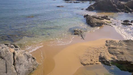 gently waves rolling into a rocky clean empty beachslow motion on 180fps