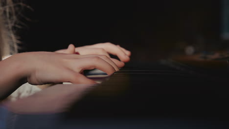 girl fingers press electric piano keys closeup. small musician learns melody during musical lessons in recording studio. new generation of musicians