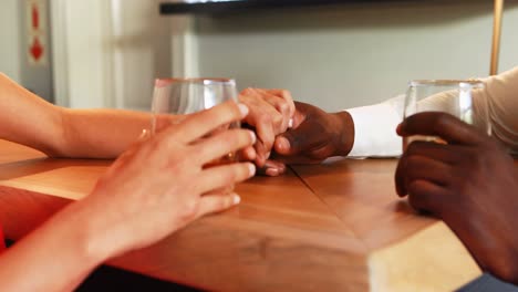 pareja sosteniendo sus manos mientras tienen whisky en el mostrador