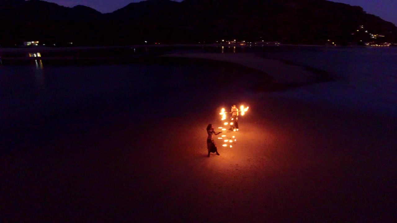 espectáculo de fuego de baile en la playa de bancos de arena al atardecer