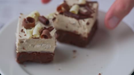 person picking three chocolate cream desserts from a white plate, rotation