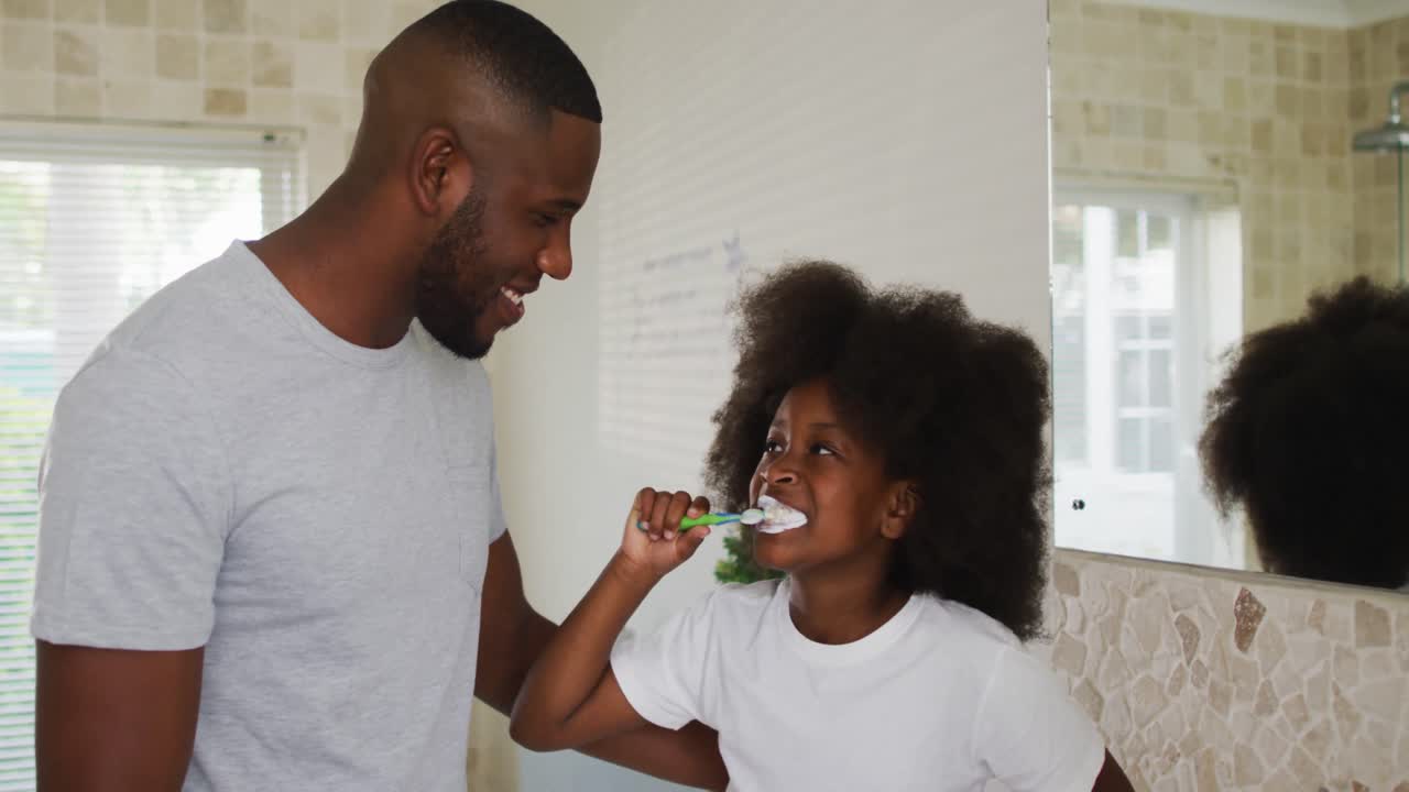 African american daughter brushing teeth and talking with her father